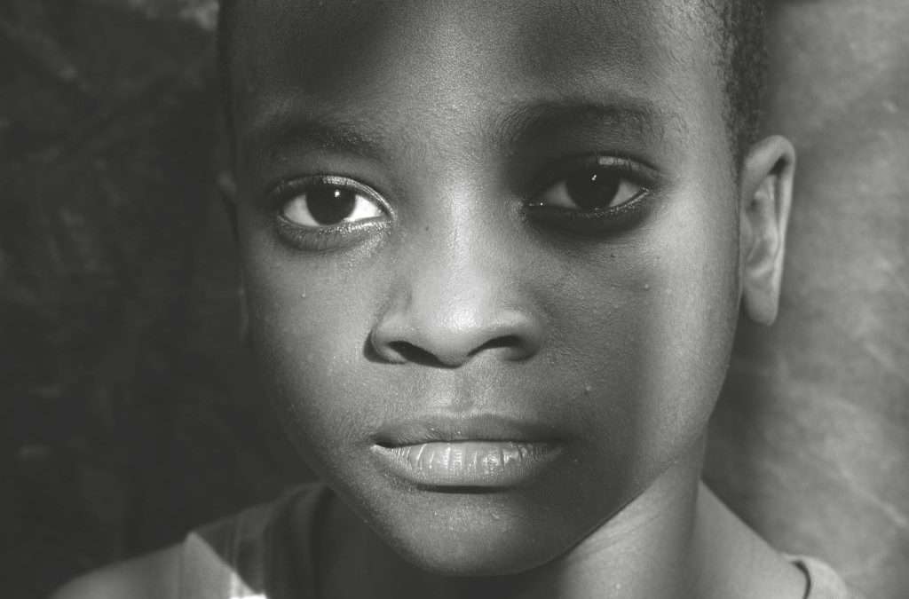 Black and white photo of young boy looking into the camera.